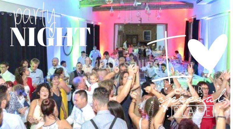 Groupe de personnes dans une salle festive, dansant et célébrant sous des lumières colorées.