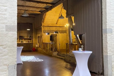 Cour pavée d'un bâtiment en pierre éclairé par des lumières extérieures, entouré d'arbres et de bâtiments annexes, de nuit.