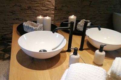 Cour pavée d'un bâtiment en pierre éclairé par des lumières extérieures, entouré d'arbres et de bâtiments annexes, de nuit.