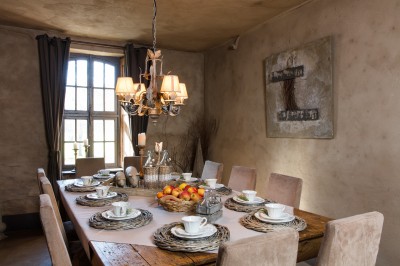 Cour pavée d'un bâtiment en pierre éclairé par des lumières extérieures, entouré d'arbres et de bâtiments annexes, de nuit.