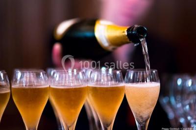 Pelouse verdoyante bordée d'arbres hauts sous un ciel bleu clair, avec une petite structure en briques à gauche.