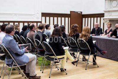 Pelouse verdoyante bordée d'arbres hauts sous un ciel bleu clair, avec une petite structure en briques à gauche.