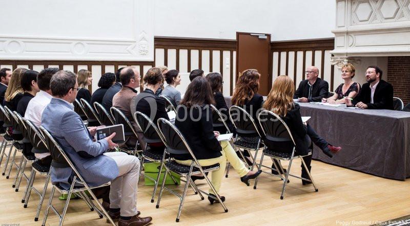 Un groupe de personnes assises dans une salle de réunion écoute un panel de quatre intervenants à une table.