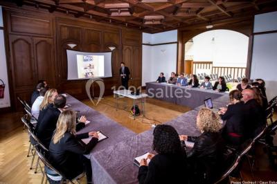 Pelouse verdoyante bordée d'arbres hauts sous un ciel bleu clair, avec une petite structure en briques à gauche.