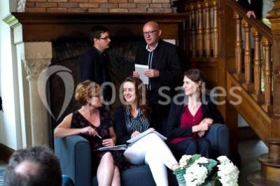 Pelouse verdoyante bordée d'arbres hauts sous un ciel bleu clair, avec une petite structure en briques à gauche.