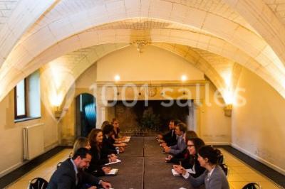 Pelouse verdoyante bordée d'arbres hauts sous un ciel bleu clair, avec une petite structure en briques à gauche.