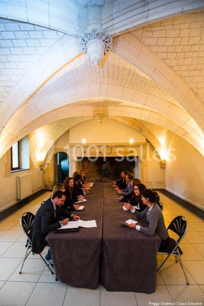 Des personnes assises autour d'une longue table dans une salle voûtée, participant à une réunion.