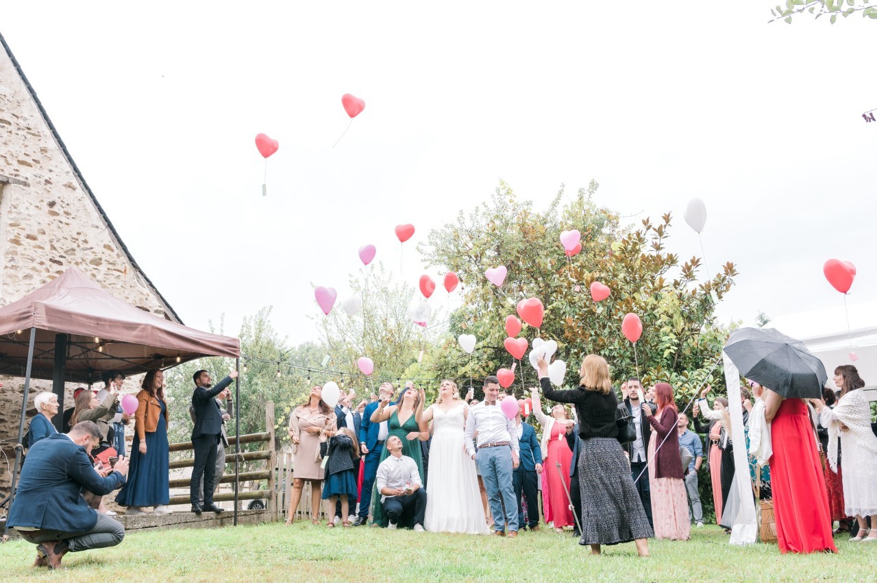 Un groupe de personnes lors d'une célébration en extérieur, libérant des ballons colorés dans le ciel.