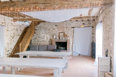 Cuisine professionnelle avec équipements en inox, plans de travail, éviers, chariots et plafond avec poutres apparentes.