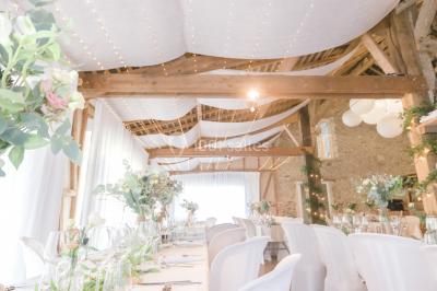 Cuisine professionnelle avec équipements en inox, plans de travail, éviers, chariots et plafond avec poutres apparentes.