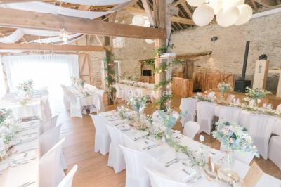 Cuisine professionnelle avec équipements en inox, plans de travail, éviers, chariots et plafond avec poutres apparentes.