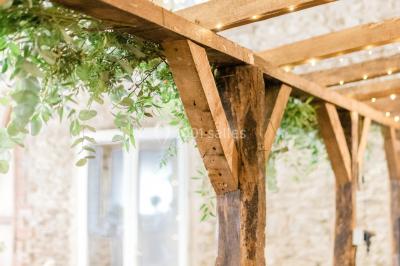 Cuisine professionnelle avec équipements en inox, plans de travail, éviers, chariots et plafond avec poutres apparentes.