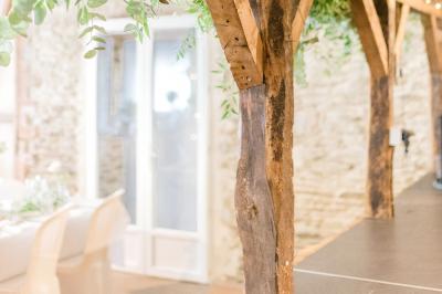 Salle de réception avec tables dressées, nappes noires, chaises blanches et parquet en bois clair.