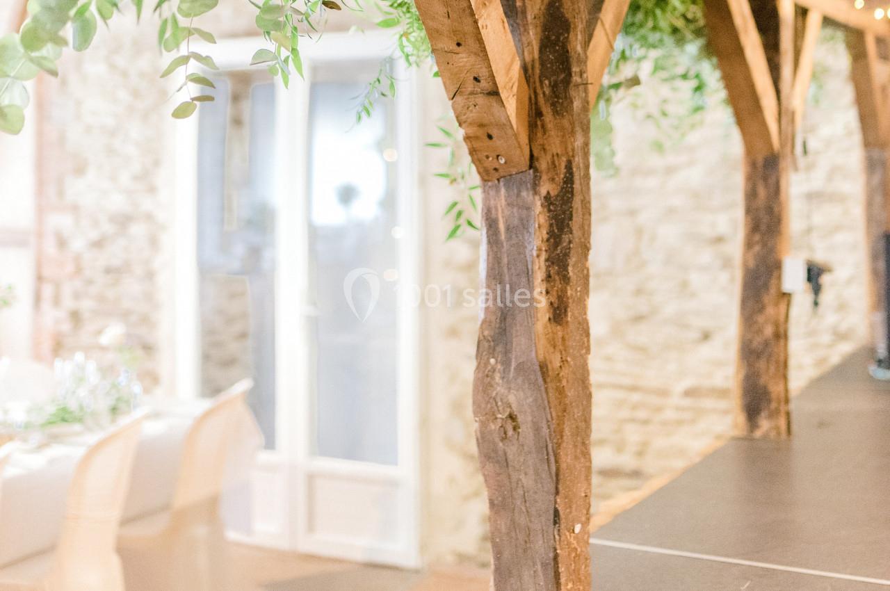 Structure en bois rustique avec des plantes suspendues, près d'une table dressée et d'une porte vitrée.