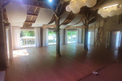 Espace intérieur avec murs en pierre, parquet en bois et comptoir décoré de guirlandes lumineuses et de feuillage.