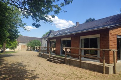 Espace intérieur avec murs en pierre, parquet en bois et comptoir décoré de guirlandes lumineuses et de feuillage.