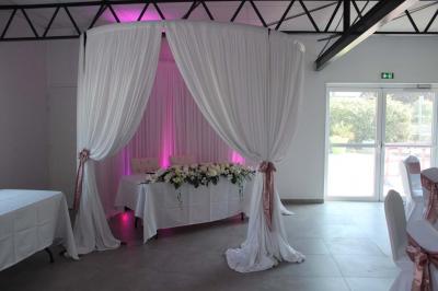 Lavabo avec miroir dans des toilettes carrelées blanches et bleues, avec urinoir visible en arrière-plan.