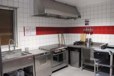 Lavabo avec miroir dans des toilettes carrelées blanches et bleues, avec urinoir visible en arrière-plan.