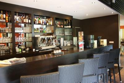 Plusieurs motos stationnées dans un parking entouré d'arbres, avec un véhicule utilitaire en arrière-plan.