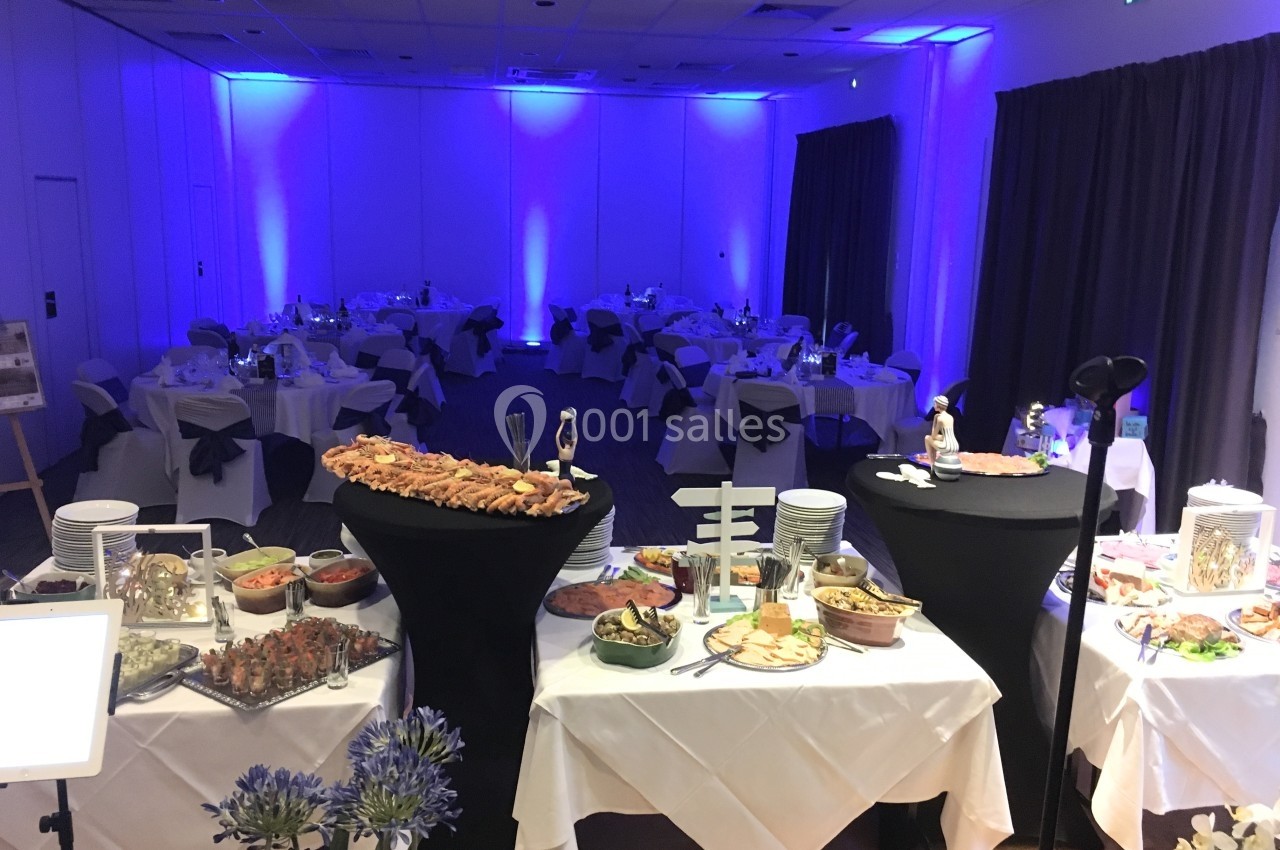 Location salle Saint-Martin-du-Vivier (Seine-Maritime) - The Originals Relais La Bertelière - Rouen #28 Salle de réception éclairée en bleu avec des tables dressées et un buffet varié au premier plan.
