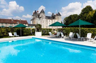 Chambre avec lit double, canapé, table basse et poutres apparentes, décorée de papier peint à motifs.