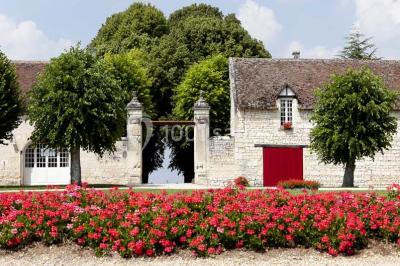 Chambre avec lit double, canapé, table basse et poutres apparentes, décorée de papier peint à motifs.