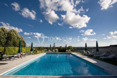 Chambre avec lit double, canapé, table basse et poutres apparentes, décorée de papier peint à motifs.