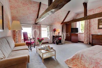 Chambre avec lit double, canapé, table basse et poutres apparentes, décorée de papier peint à motifs.