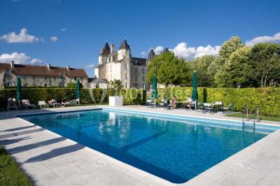 Chambre avec lit double, canapé, table basse et poutres apparentes, décorée de papier peint à motifs.