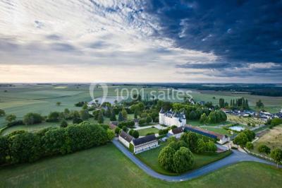 Chambre avec lit double, canapé, table basse et poutres apparentes, décorée de papier peint à motifs.