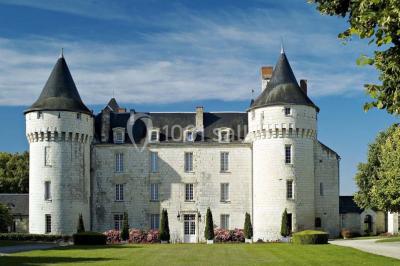 Chambre avec lit double, canapé, table basse et poutres apparentes, décorée de papier peint à motifs.