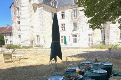 Chambre avec lit double, canapé, table basse et poutres apparentes, décorée de papier peint à motifs.
