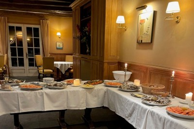 Chambre avec lit double, canapé, table basse et poutres apparentes, décorée de papier peint à motifs.