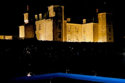 Chambre avec lit double, canapé, table basse et poutres apparentes, décorée de papier peint à motifs.