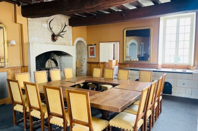 Chambre avec lit double, canapé, table basse et poutres apparentes, décorée de papier peint à motifs.