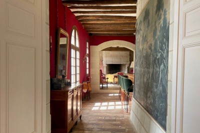 Chambre avec lit double, canapé, table basse et poutres apparentes, décorée de papier peint à motifs.