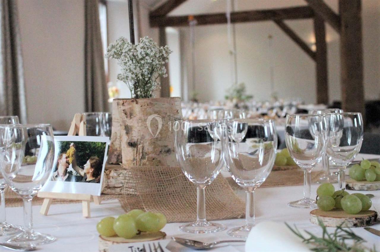 Table décorée pour un événement avec des verres à vin, des grappes de raisin et un centre de table en bois et fleurs…