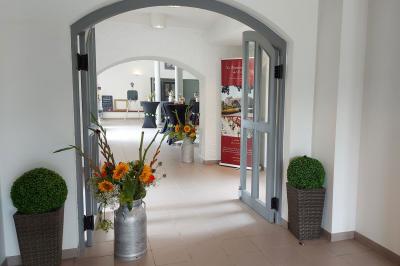 Vue aérienne d'un complexe avec plusieurs bâtiments, un jardin central, un parking et des zones identifiées par des noms.