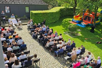 Vue aérienne d'un complexe avec plusieurs bâtiments, un jardin central, un parking et des zones identifiées par des noms.