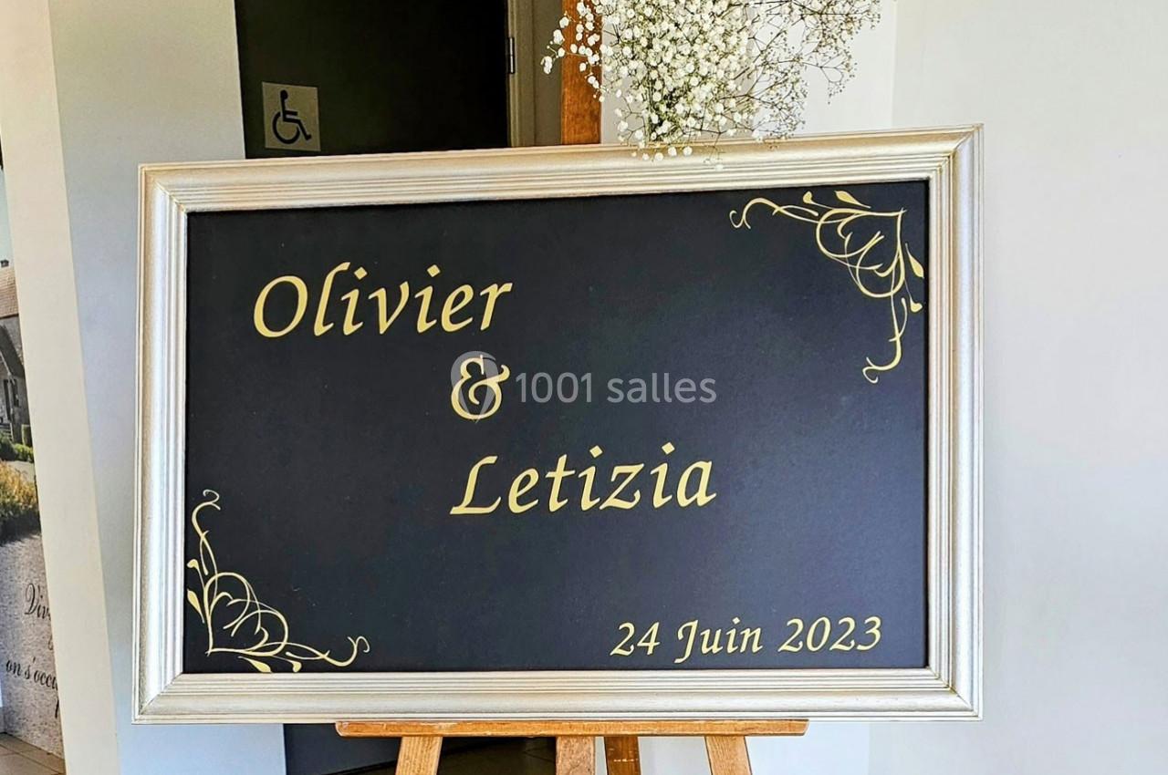 Panneau noir encadré avec les prénoms ’Olivier & Letizia’ et la date ’24 Juin 2023’, décoré de motifs dorés.