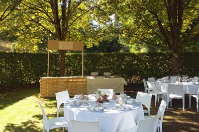 Vue aérienne d'un complexe avec plusieurs bâtiments, un jardin central, un parking et des zones identifiées par des noms.