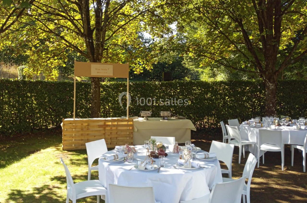 Tables dressées pour un repas en extérieur sous des arbres, avec un buffet en arrière-plan.