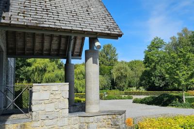 Vue aérienne d'un complexe avec plusieurs bâtiments, un jardin central, un parking et des zones identifiées par des noms.