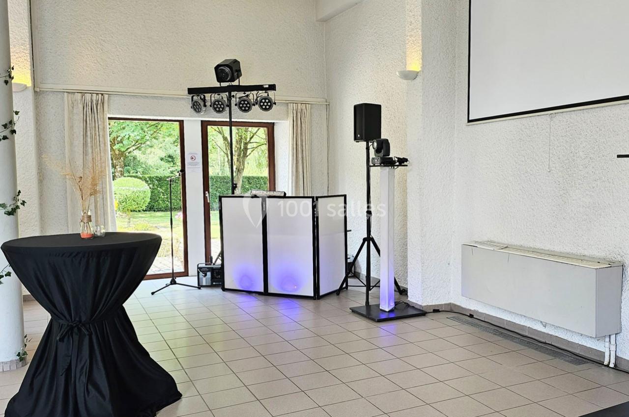 Matériel de sonorisation et éclairage installé dans une salle lumineuse avec vue sur un jardin.