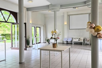 Vue aérienne d'un complexe avec plusieurs bâtiments, un jardin central, un parking et des zones identifiées par des noms.