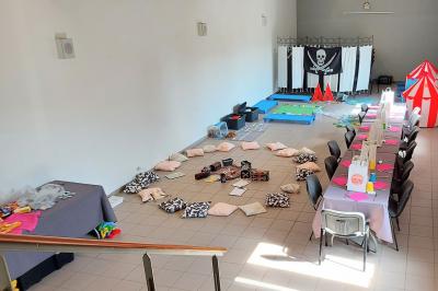 Vue aérienne d'un complexe avec plusieurs bâtiments, un jardin central, un parking et des zones identifiées par des noms.