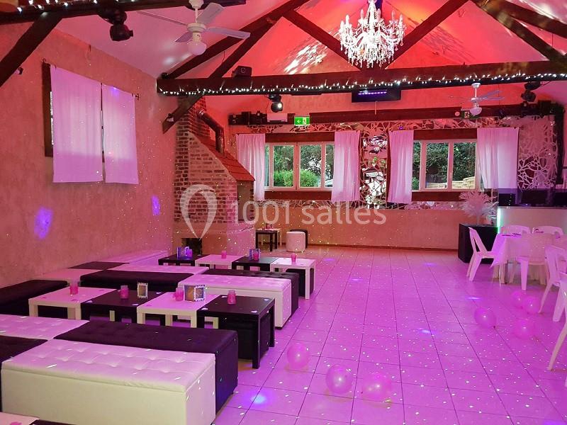 Salle décorée pour un événement, avec canapés, ballons au sol, lustre et éclairage coloré.