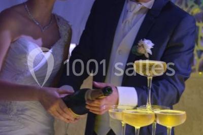 Pièce montée en forme d'anneaux entrelacés avec des figurines de mariés, entourée de bouteilles de champagne.