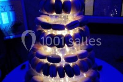 Pièce montée en forme d'anneaux entrelacés avec des figurines de mariés, entourée de bouteilles de champagne.