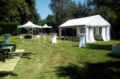 Pièce montée en forme d'anneaux entrelacés avec des figurines de mariés, entourée de bouteilles de champagne.